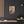 Canvas wall art with a bold burgundy and beige illustration of ancient Greek playwright Sophocles on a dark wall above a shelf