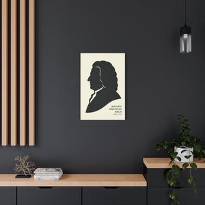 Canvas wall art with a black on ivory silhouette illustration of musician Johann Sebastian Bach on a dark wall with wooden shelves and decor.