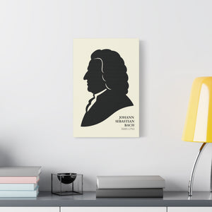 Canvas wall art with a black on ivory silhouette illustration of musician Johann Sebastian Bach on a wall above a desk with books and a lamp.