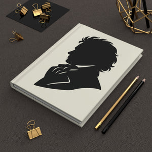 Hardcover journal with a black on ivory silhouette illustration of musician Ludwig van Beethoven on a dark surface with office supplies.