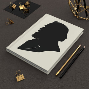 Hardcover journal with a black-on-ivory silhouette illustration of musician Johannes Brahms on a dark surface with office supplies.