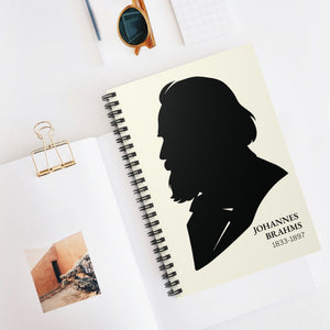 Spiral notebook with a black on ivory silhouette illustration of musician Johannes Brahms on a white surface