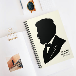 Spiral notebook with a black on ivory silhouette illustration of musician Claude Debussy on a white surface.