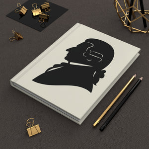 Hardcover journal with a black on ivory silhouette illustration of musician Joseph Haydn on a dark surface with office supplies.