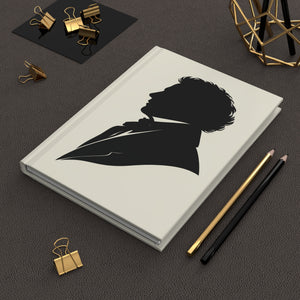 Hardcover journal with a black-on-ivory silhouette illustration of musician composer Franz Schubert on a dark surface with office supplies.