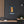 Canvas wall art with a bold illustration of philosopher Baruch Spinoza on a dark wall with a wooden shelf and plant in the foreground