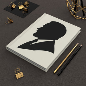 Hardcover journal with a black on ivory silhouette illustration of musician Pyotr Ilyich Tchaikovsky on a dark surface with office supplies.