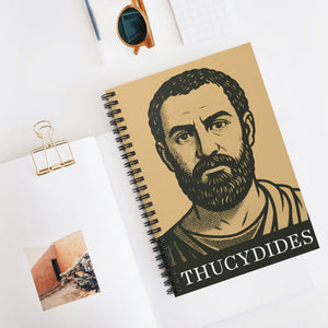 Spiral notebook with a bold black and beige illustration of ancient Greek historian Thucydides lying flat on a white surface with other items for context