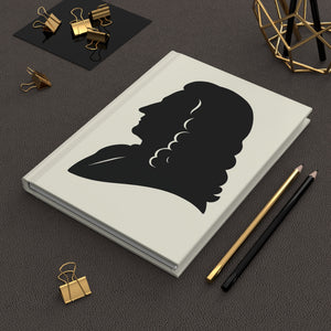 Hardcover journal with a black on ivory silhouette illustration of musician Antonio Vivaldi on a dark surface with office supplies.
